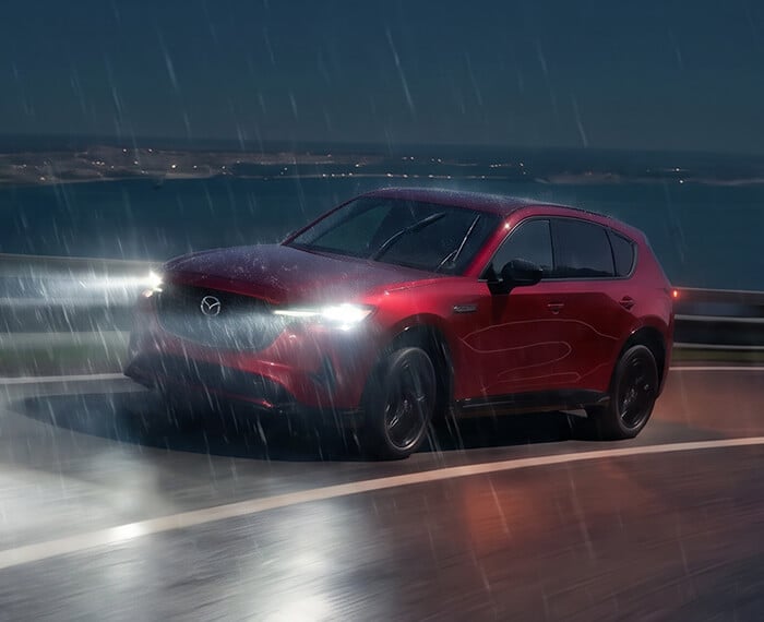 Mazda CX-5 driving on a winding road in heavy rain at night.