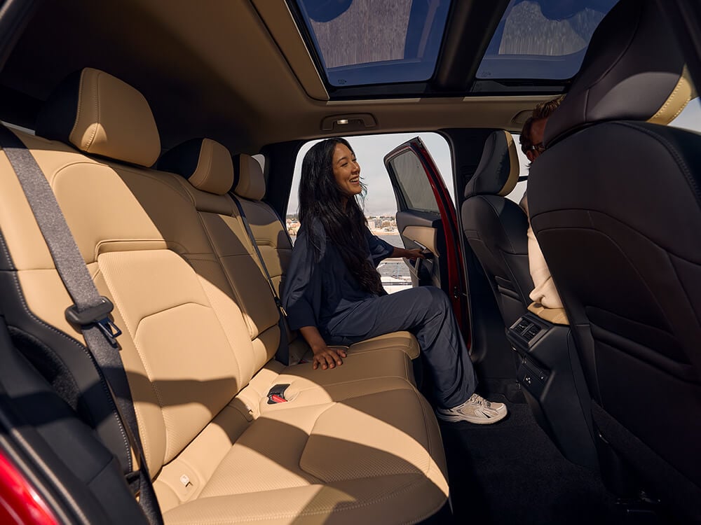 Femme prenant place sur le siège arrière d'un Mazda CX-5, vue par la port arrière du côté opposé.