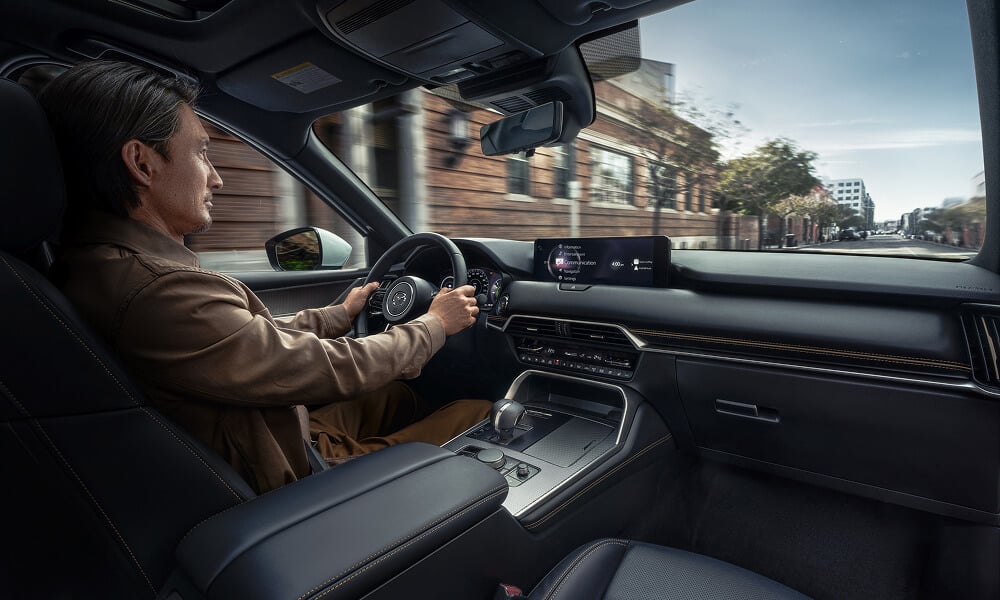 A man driving the CX-90 shot from the front passenger side.