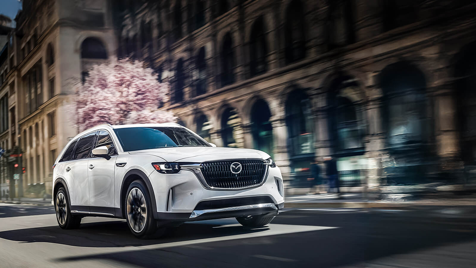 Une Mazda3 platine garée dans la rue.