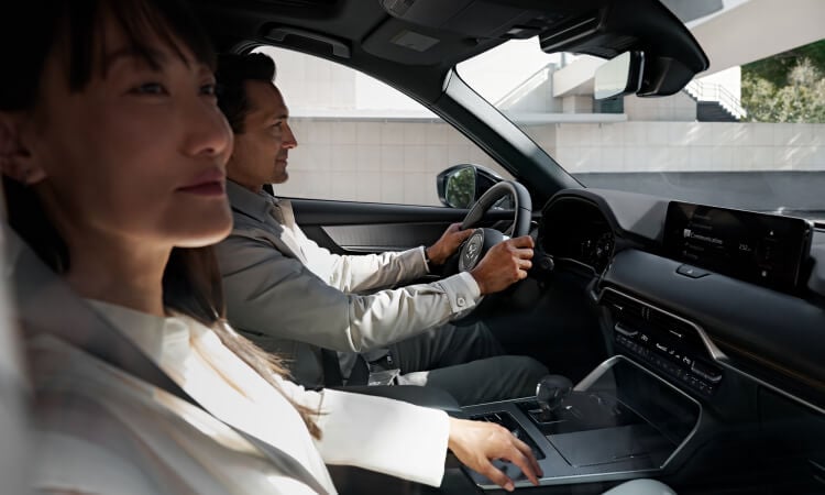 Side profile of a woman and man driving the CX-70.